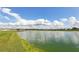 Scenic pond view with blue skies and fluffy white clouds and community homes in the distance at 2122 Rosewood Dr, Bartow, FL 33830