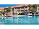 Exterior shot of a community pool with palm trees, lounge chairs, and a multi-story building backdrop at 6337 Parc Corniche Dr # 2101, Orlando, FL 32821