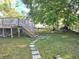 A spacious backyard with a wooden deck, stairs, and mature trees at 663 Hager St, Deltona, FL 32725