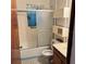 Modest bathroom with tub/shower combo, white tile, blue trim, and linen storage at 102 Center Sw St, Winter Haven, FL 33880