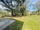 Expansive backyard featuring green lawn, mature trees and utility shed on a sunny day at 301 Bassedena N Cir, Lakeland, FL 33805