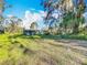 Exterior view of the home showcasing the well-manicured lawn and mature trees at 305 Bearcreek Dr, Bartow, FL 33830