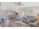 Open-concept living room with wood floors, ceiling fan, view of dining area, and comfortable gray sectional sofa at 17 Se 61St Ct, Ocala, FL 34472