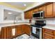 Well-lit kitchen features stainless steel appliances and wooden cabinets and an open window to the other room at 2500 21St Nw St # 88, Winter Haven, FL 33881