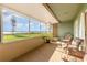 Enclosed porch with decorative chairs and a view of the well-manicured backyard and lake at 2500 21St Nw St # 88, Winter Haven, FL 33881