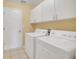 Bright laundry room featuring a washer, dryer, and ample storage space with white cabinets at 21505 Castle View Ct, Leesburg, FL 34748