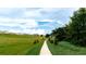 Scenic walking path through a green field with residential houses in the distance at 2611 Skyline Loop, Kissimmee, FL 34758