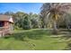 Large backyard with lush green grass, palm trees, and an outdoor seating area at 5670 Sw 34Th St, Ocala, FL 34474