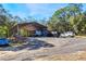 Exterior shot of a covered shelter with a RV, trucks parked nearby, gravel drive, and lush trees around at 12308 Se 112Th Avenue Rd, Belleview, FL 34420