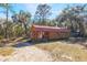 Exterior shot of a wood house with red roof and covered porch, surrounded by trees at 12308 Se 112Th Avenue Rd, Belleview, FL 34420