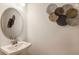 Modern powder room with a pedestal sink, a round mirror, and decorative wall art at 16198 Honey Harvest St, Winter Garden, FL 34787