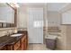 Well-maintained bathroom with dark wood cabinets, black granite countertops, and tub with tile surround at 7615 Heritage Crossing Way # 102, Reunion, FL 34747