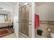 Bathroom with a tiled walk-in shower with glass doors, red towel, toilet and black trash can at 7615 Heritage Crossing Way # 102, Reunion, FL 34747