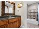 Bathroom featuring granite counters, wood cabinets, decorative mirror, and shower-tub combination at 7615 Heritage Crossing Way # 102, Reunion, FL 34747