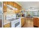 Cozy kitchen featuring light wood cabinets, tile floors, and white appliances at 848 Casselberry Dr, Lake Wales, FL 33853