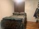 Comfortable bedroom with a full bed and a camo bedspread. Hardwood flooring and wood paneling throughout at 24605 Ne 177Th Ter, Fort Mc Coy, FL 32134