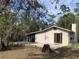 Tan home featuring a chimney, brick patio, double doors, and a beautiful landscape with trees at 24605 Ne 177Th Ter, Fort Mc Coy, FL 32134
