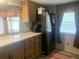 Functional kitchen with stainless steel refrigerator, wood cabinets, and a view through the window at 24605 Ne 177Th Ter, Fort Mc Coy, FL 32134