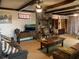 Cozy living room featuring exposed wood beams, a stone fireplace, and comfortable seating at 24605 Ne 177Th Ter, Fort Mc Coy, FL 32134