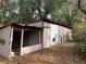 Exterior side view of shed with corrugated metal roof, concrete walls, and faded pink trim, showing outdoor hose connection at 24605 Ne 177Th Ter, Fort Mc Coy, FL 32134