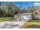 Charming single-story home featuring an attached two-car garage and a long driveway in a verdant, wooded setting at 4111 Se 131St Ln, Belleview, FL 34420