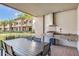 Covered outdoor dining area with a built-in grill and tropical landscaping at 7540 Brooklyn Dr, Kissimmee, FL 34747