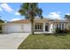 Charming single-story home featuring a lush front yard, a three car garage, and a welcoming blue front door at 113 Grand Reserve Ct, Davenport, FL 33837