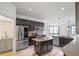 Modern kitchen with dark cabinetry, granite countertops, stainless steel appliances, and center island and adjacent living area at 113 Grand Reserve Ct, Davenport, FL 33837