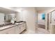 Bright bathroom with dual sinks, granite countertops, modern fixtures, large mirror and open access to the walk-in closet at 3217 Armstrong Ave, Clermont, FL 34714