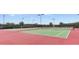 Green and red tennis courts inside of a community featuring a net and lighting for evening play at 3217 Armstrong Ave, Clermont, FL 34714