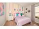 Bright bedroom with rainbow-colored accent wall, pink bed, and whimsical decorations at 1010 Foreshore Ln, Haines City, FL 33844