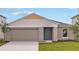 Charming single-story home featuring a light blue front door, beige siding, and a two-car garage at 1010 Foreshore Ln, Haines City, FL 33844