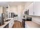 Well-lit kitchen with stainless steel appliances, white cabinetry, stone countertops, and wood flooring at 1010 Foreshore Ln, Haines City, FL 33844
