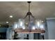 Close-up of a modern chandelier with glass shades, with the kitchen in the background at 5118 Norriswood Dr, Mulberry, FL 33860