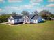 Charming single-Gathering home featuring a classic white exterior, dark shutters, a welcoming porch, and lush green lawn at 5118 Norriswood Dr, Mulberry, FL 33860
