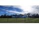 Charming white home with a gabled roof and a well-manicured lawn surrounded by a black chain-link fence at 5118 Norriswood Dr, Mulberry, FL 33860