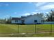Picturesque view of home from yard behind a black perimeter fence and blue sky at 5118 Norriswood Dr, Mulberry, FL 33860