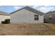A view of the backyard, showing the siding and window detail of the home at 1654 Indigo Ave, The Villages, FL 32162
