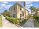 Exterior view of a yellow two-story townhouse with lush landscaping, sidewalks, and a blue sky with scattered clouds at 5331 River Rock Rd, Lakeland, FL 33809