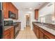 Functional kitchen with black appliances, tile flooring, cherry wood cabinets and view to hall bathroom at 5331 River Rock Rd, Lakeland, FL 33809