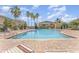 A serene community pool surrounded by lounge chairs, palm trees, and a black iron fence against a blue sky backdrop at 5331 River Rock Rd, Lakeland, FL 33809