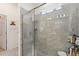 Shower with pebble floor, glass door, gray tile, window, showerhead, and toiletry shelf at 4763 Riverwalk Dr, St Cloud, FL 34771