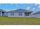 Backyard view of the home featuring a large grass area and simple exterior at 1040 Cambridge Drive, Winter Haven, FL 33881