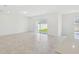 Large, vacant living room with tile floors and sliding glass doors leading to a grassy backyard at 276 Woodsage Pl, Lake Alfred, FL 33850