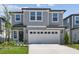 Two-story home featuring a two-car garage, well-manicured lawn, and a classic gray and white color scheme at 284 Woodsage Pl, Lake Alfred, FL 33850
