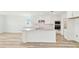 Bright, all-white kitchen featuring an island, modern appliances, white countertops, and light wood floors at 284 Woodsage Pl, Lake Alfred, FL 33850