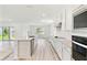 Open-concept kitchen with an island, modern appliances, white cabinets and countertops, seamlessly connected to living area at 284 Woodsage Pl, Lake Alfred, FL 33850