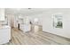 Bright, open-concept living space with light wood floors, white walls, and kitchen access at 284 Woodsage Pl, Lake Alfred, FL 33850