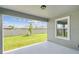 Covered patio overlooking a grassy backyard with a white fence and young tree at 284 Woodsage Pl, Lake Alfred, FL 33850