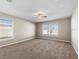 Spacious bedroom with neutral carpet, a ceiling fan, and natural light from two windows at 524 Buckshot Ln, Lakeland, FL 33809